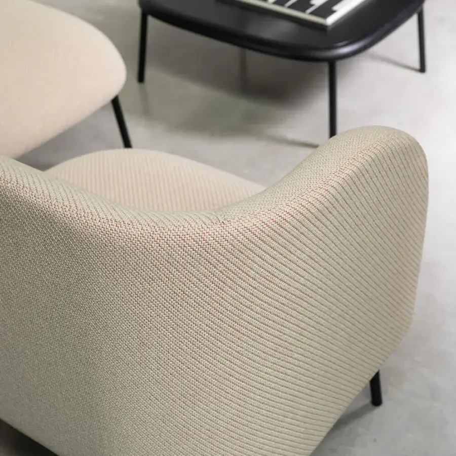 Elegant Bross Sit lounge chair with woven light beige fabric upholstery and slender dark metal legs crafted in Italy with a matte finish
