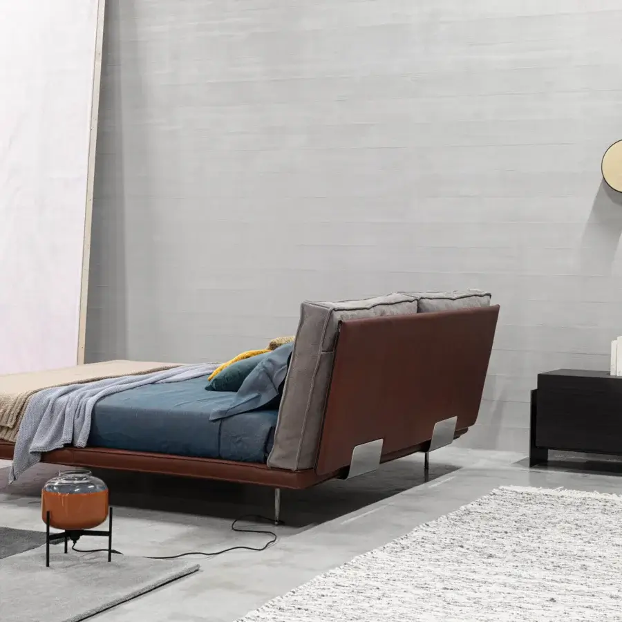Superior Cierre1972 Divine bed with brown leather-like upholstery and gray textile cushions resting on thin metal legs