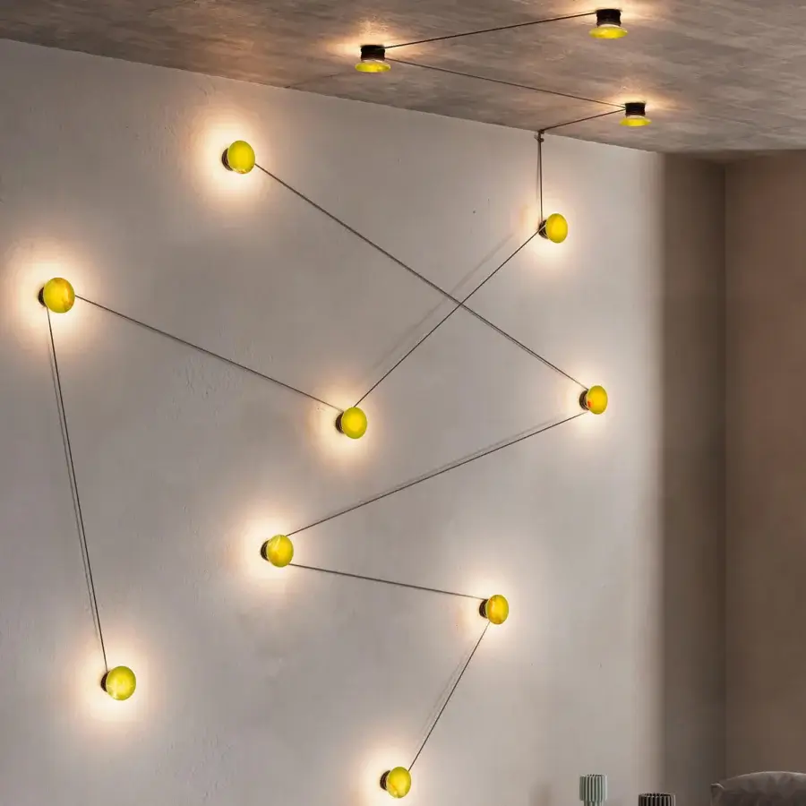 Superior Kundalini Azou wall lamp with painted metal, onyx or marble discs, and slender black wires creating a geometric pattern