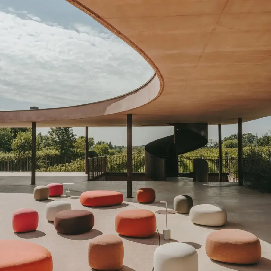 Captivating Lapalma Kipu outdoor ottoman with curved form upholstered in UV stable outdoor fabric with orange, red, brown and white hues