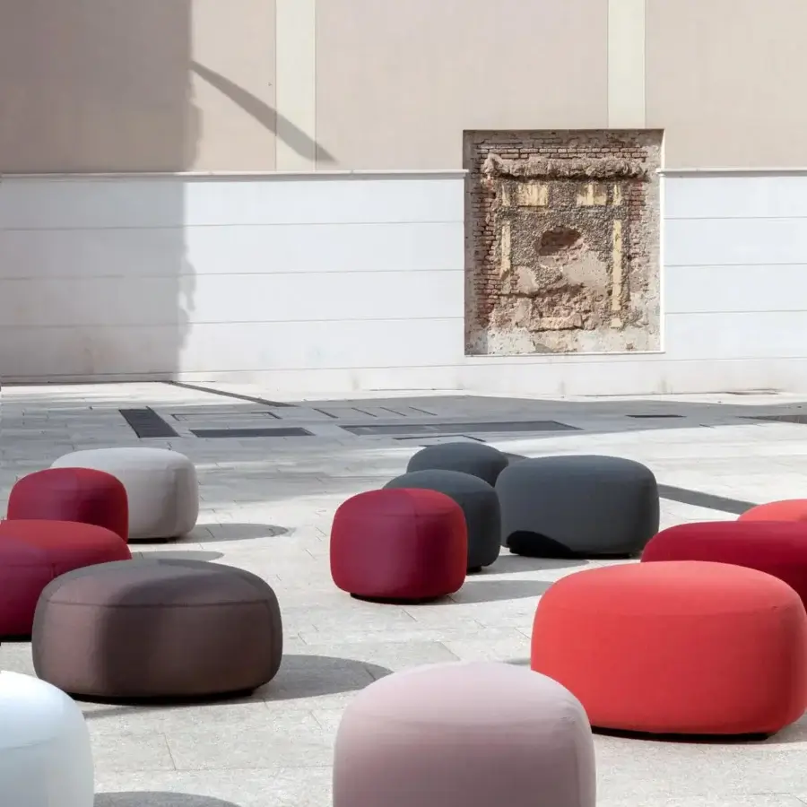 Distinguished Lapalma Kipu outdoor ottoman with cylindrical form upholstered in red, pink, brown, white, and gray UV-stable fabric with marine plywood base