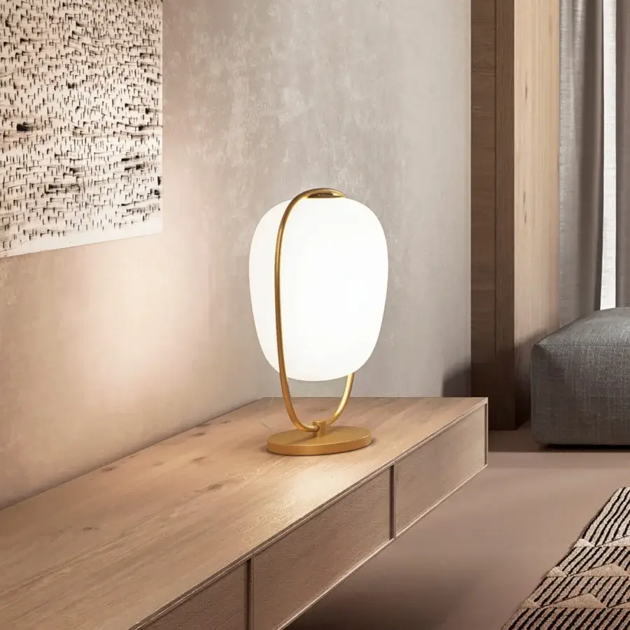 Elegant Kundalini Lannà table lamp with an opal glass diffuser and metallic coated curved structure in gold finish