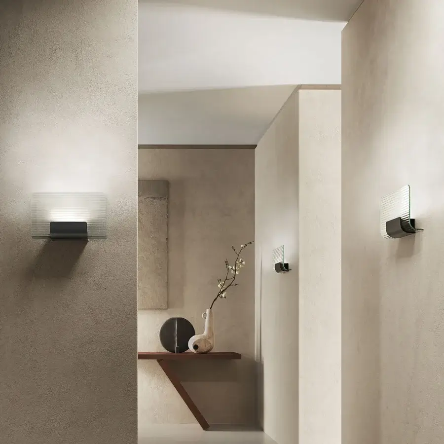 Elegant Kundalini Nami wall lamp with curved clear glass diffuser and varnished die-casted aluminum structure