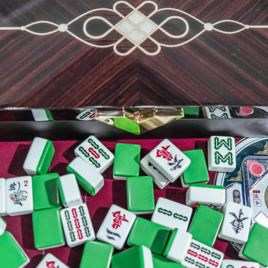 Exceptional Vismara Ming Mahjong table built with reddish-brown lacquered wood and steel, showcasing a symmetrical knotted inlay with a red velvet surface