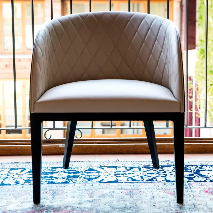 Superior Bross Hug armchair in light beige leather with quilted detailing and dark wood frame