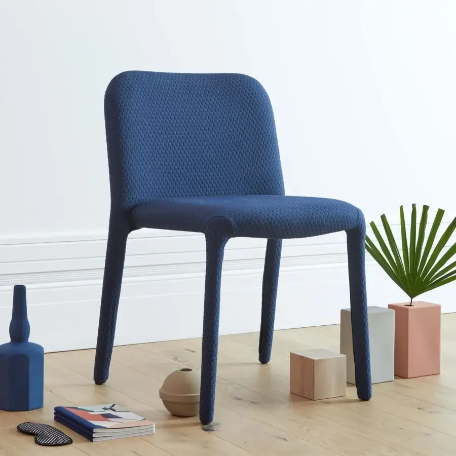 Elegant Miniforms Pelè chair completely padded in textured blue textile with curved lines and seamless silhouette