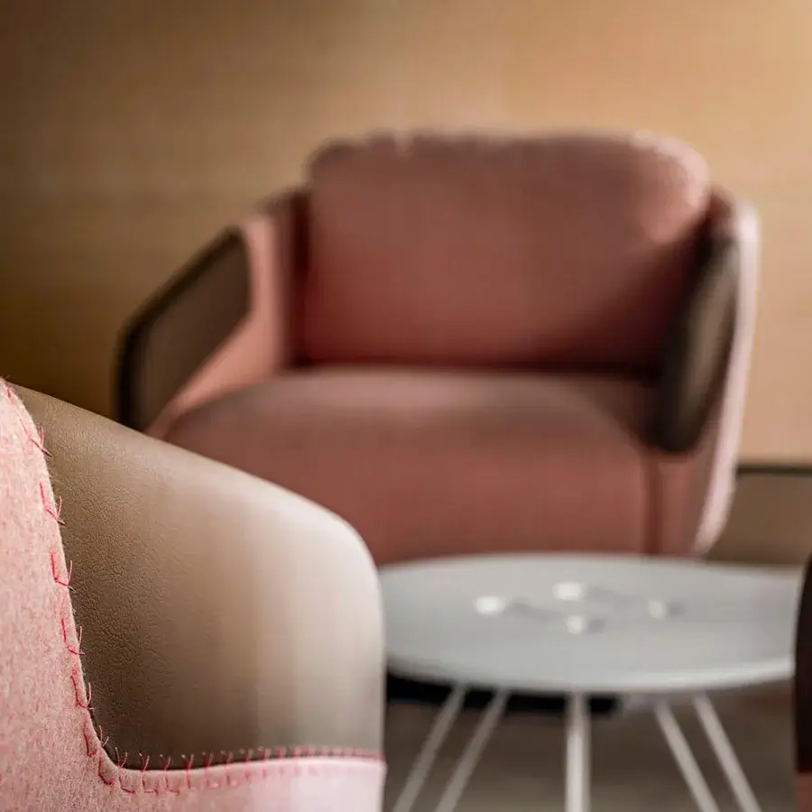 Exceptional Casamania Worn lounge chair fully upholstered in light pink textured fabric with light brown faux leather armrests and decorative stitching