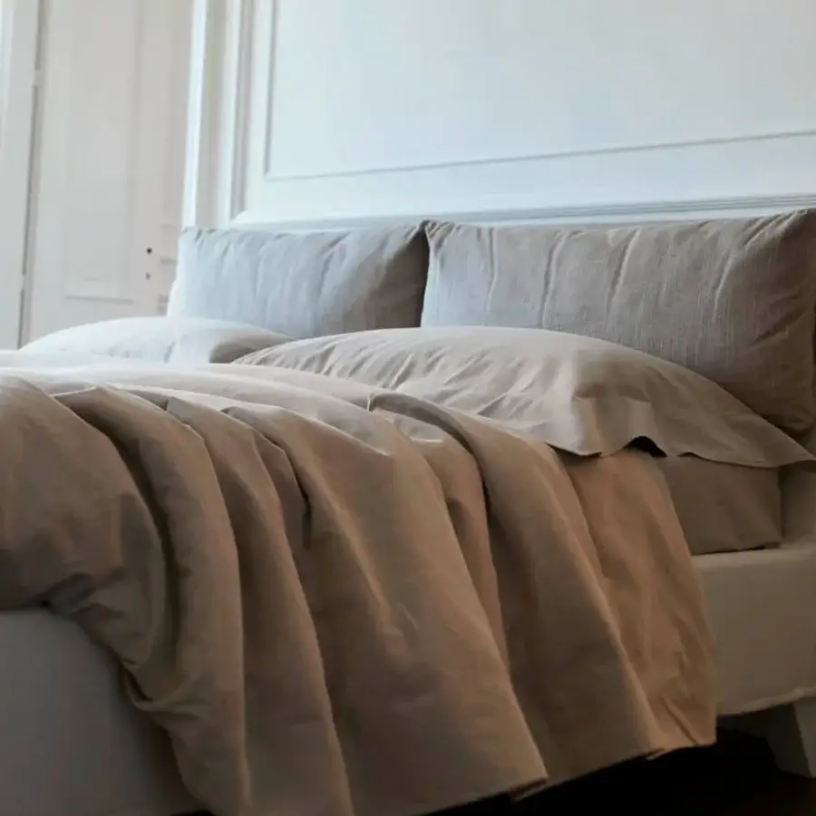 Superior Horm Bahamas bed with light grey linen-like textile, square pillows and mocha-finished solid beechwood legs