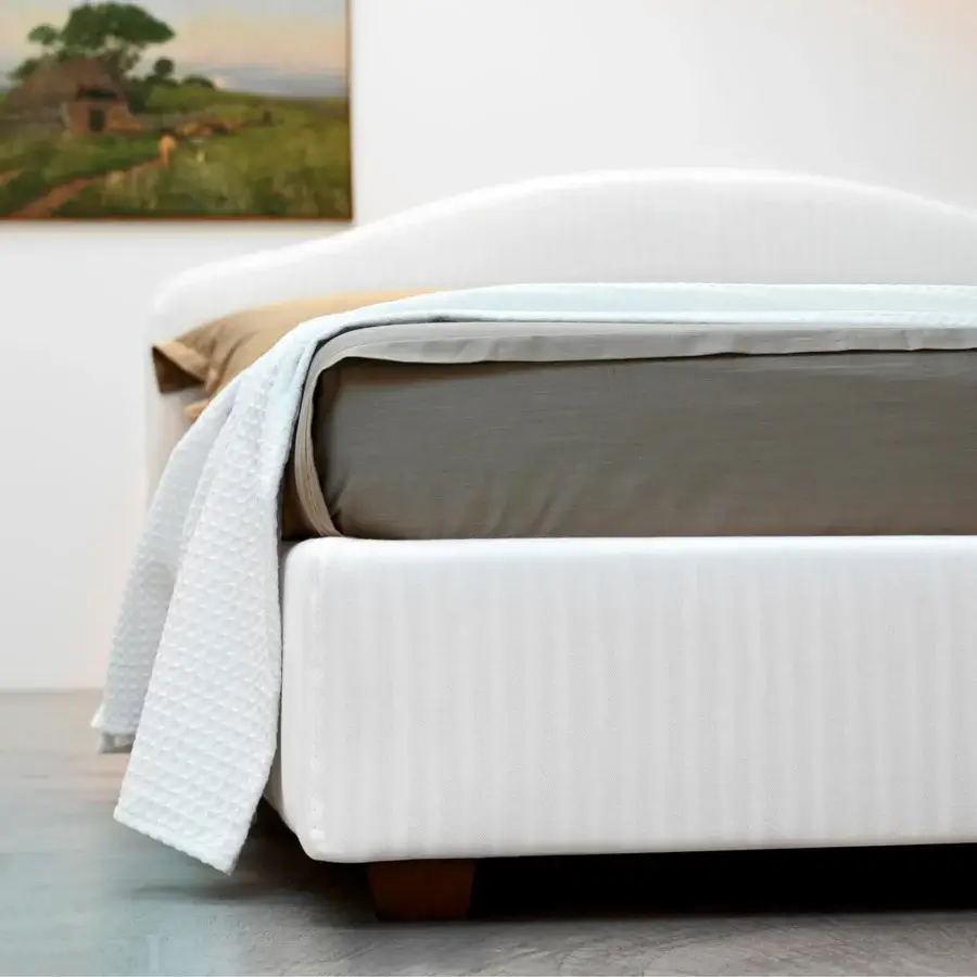 Elegant Horm Elba bed with curved headboard upholstered in white textile and mocha lacquered beechwood legs