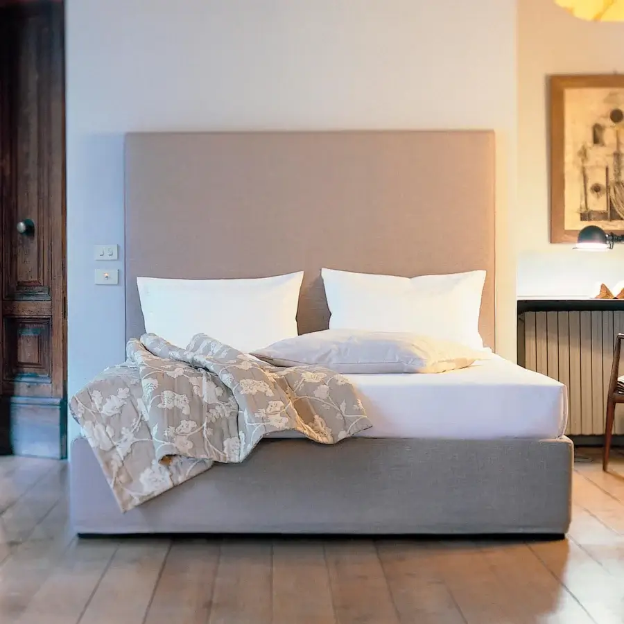 Elegant Horm Panarea bed with neutral fabric upholstery and mocha lacquered solid beechwood feet