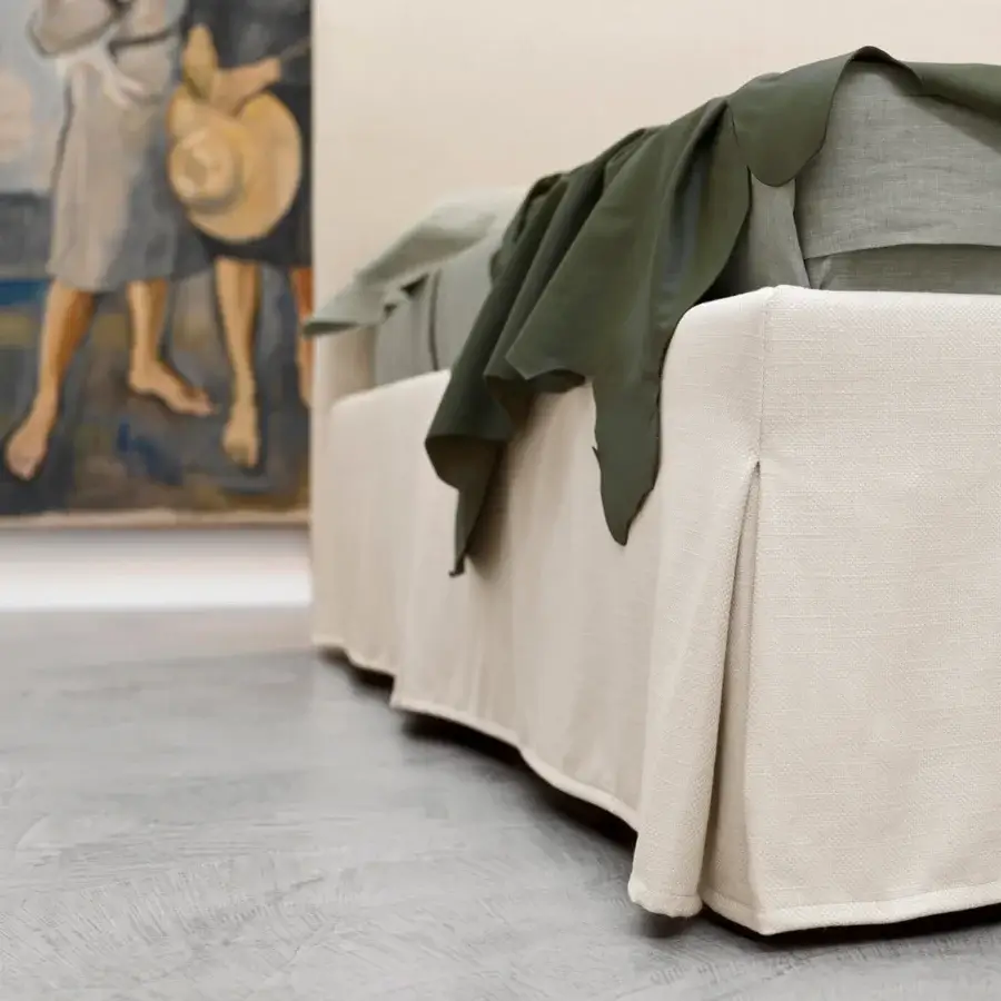 Distinguished Horm Sardegna bed with skirted design and light beige textile cover supported by natural lacquer beechwood feet