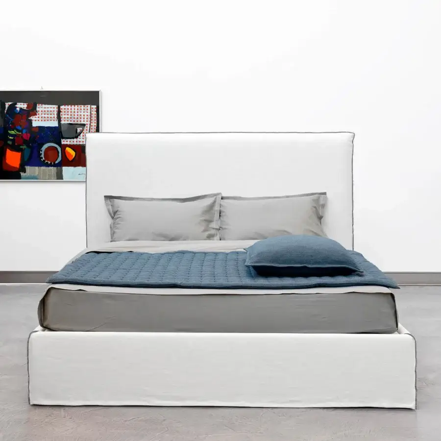 Elegant Horm Tahiti bed with light textile upholstery, subtle gray piping and white lacquered beechwood feet