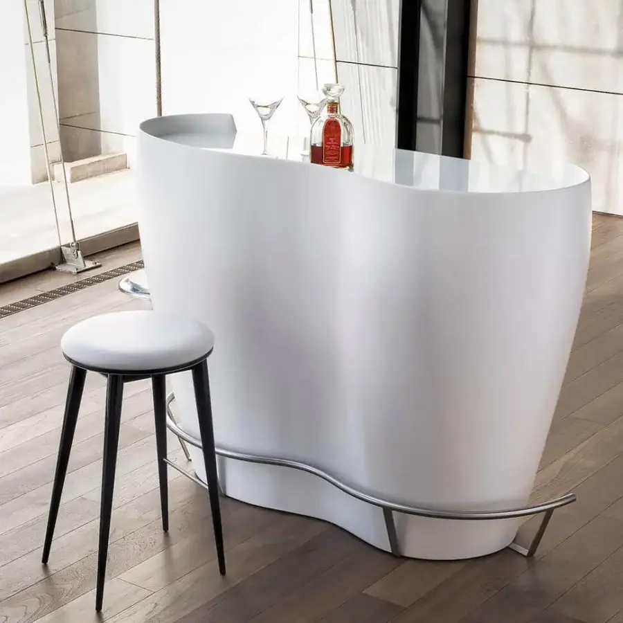 Sophisticated Coco de Mer bar with organically shaped white glossy structure and clear glass countertop complemented by a curved metal footrest