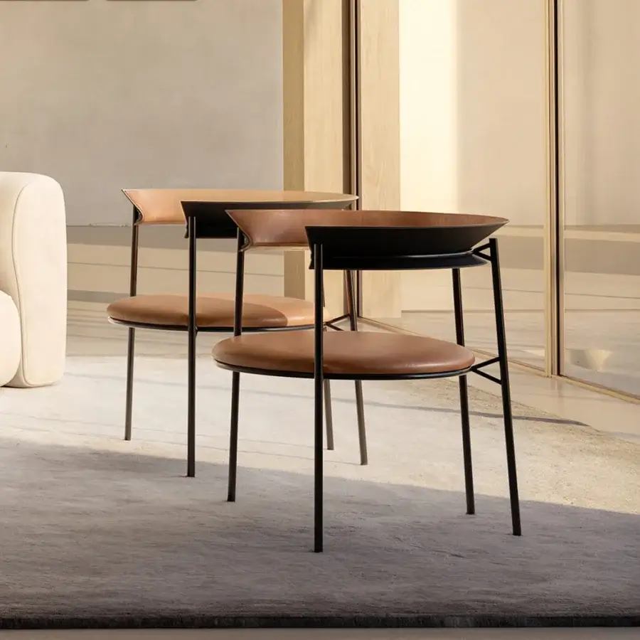 Elegant MDF Italia Cantle lounge chair with curved backrest upholstered in warm tan and saddle leather with graphite grey powder coating