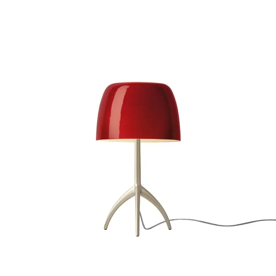 Foscarini Lumiere Piccola table lamp, cherry champagne, glossy red rounded shade with silver stem and three curved metallic legs.