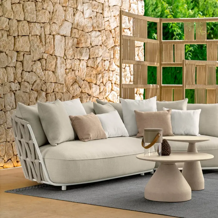 Sophisticated Talenti Swipe sofa exhibits lightness with soft light beige cushions and a dynamic tan rope weave aluminum backrest