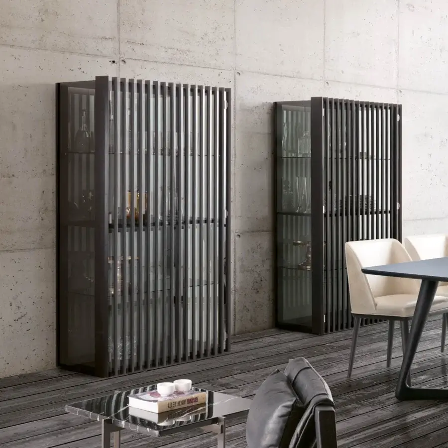 Gray bay showcase units with metal slats and glass panels flank a dining set with a light gray table and upholstered chairs.