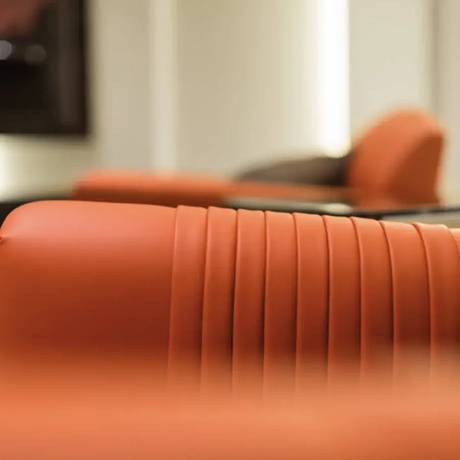 Distinguished Turri Madison lounge chair upholstered in warm orange leather with stylish vertical embroidery
