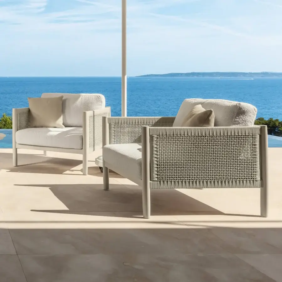 Distinguished Talenti Dolcevita Alu lounge chair with light metal frame and woven synthetic sides cradling light cream cushions
