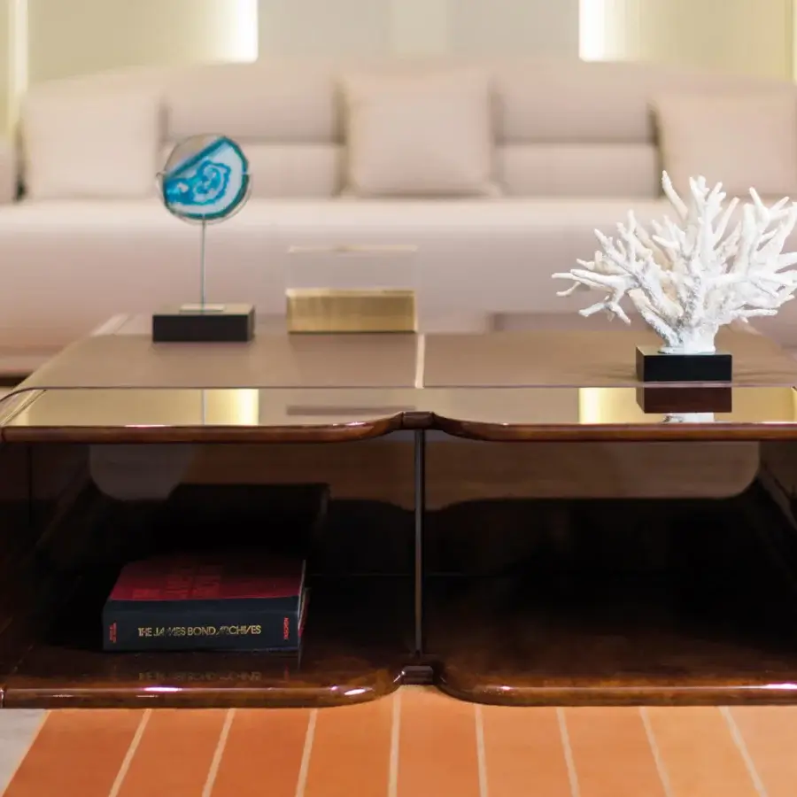 Distinguished Turri Madison coffee table with a curved design and glossy dark brown wood finish accented with light gold metal and leather