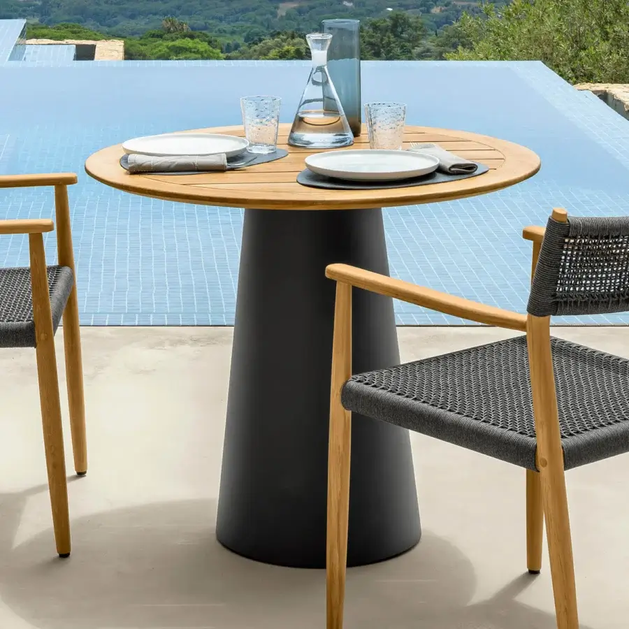 Distinguished Talenti Dolcevita Wood round table with teak top and dark cylindrical base exhibiting a smooth finish