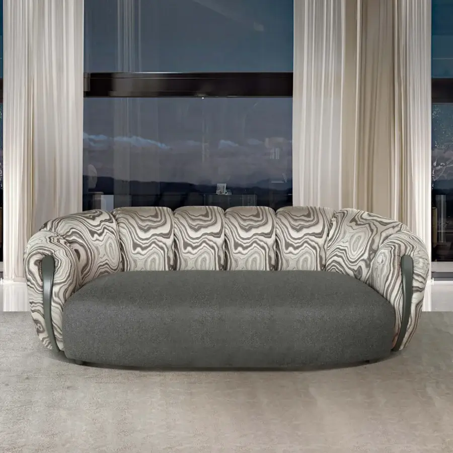 Belmondo stone sofa, beige marbled pattern, rounded low profile with quilted backrest and dark gray trim on a light gray rug.