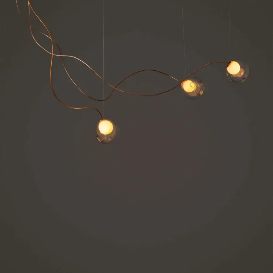 Superior Bocci 28 sculptural lamp with reddish-brown rods and clear glass spheres emitting a warm yellow glow