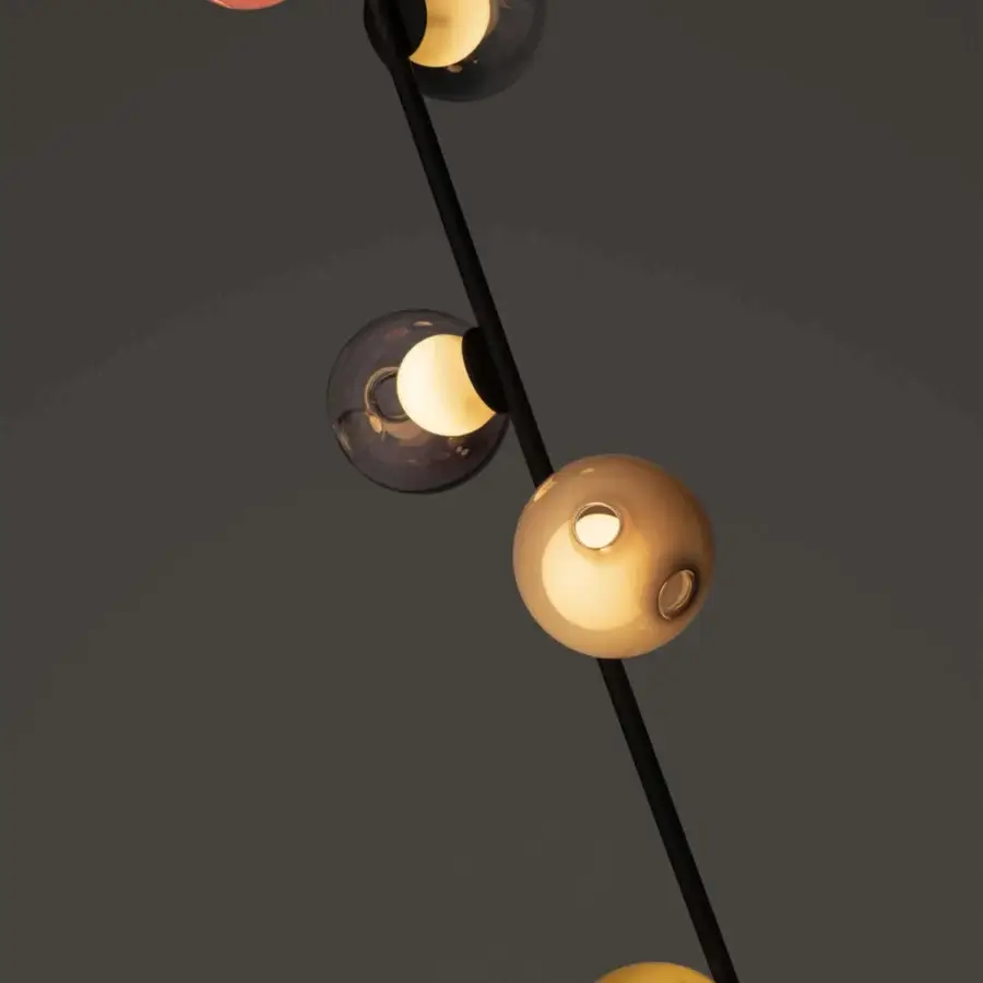 Distinguished Bocci 28 Stem Floor to Ceiling Lamp with a black finish and diagonally oriented stem suspending tonal amber and gold glass shades