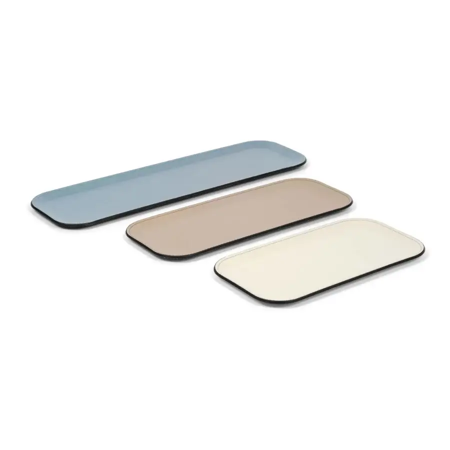 Rectangular trays from Pinetti’s Victor collection, muted blue, beige, and cream, with black trim and beveled edges, studio shot.