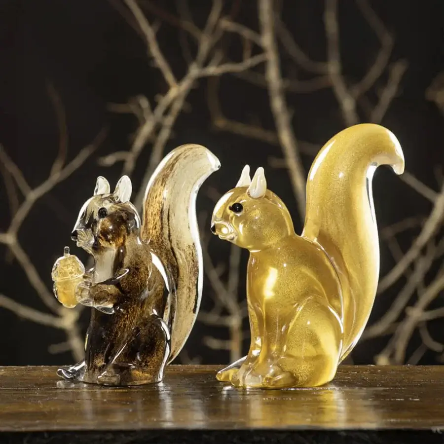 Glass squirrel sculptures by Duccio Di Segna on dark wood, featuring amber and gold tones, translucent forms, and curled tail details.