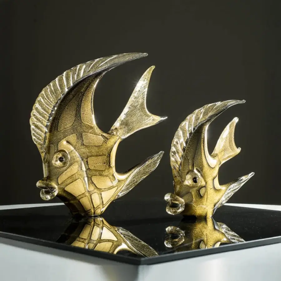 Gold fish sculptures by Duccio Di Segna on black reflective surface, featuring textured metallic glass with curved fins and detailed features.