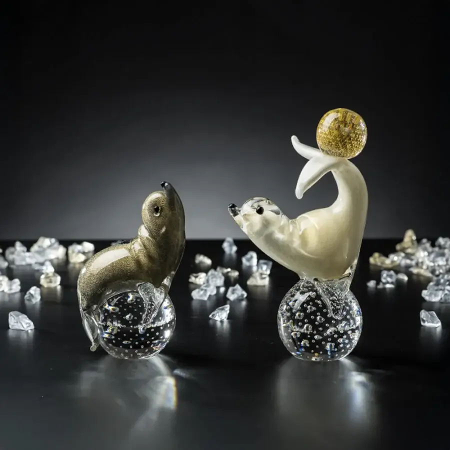 Glass seal sculptures by Duccio Di Segna on spheres with gold flecks, displayed against a dark gray backdrop with crystal shards.
