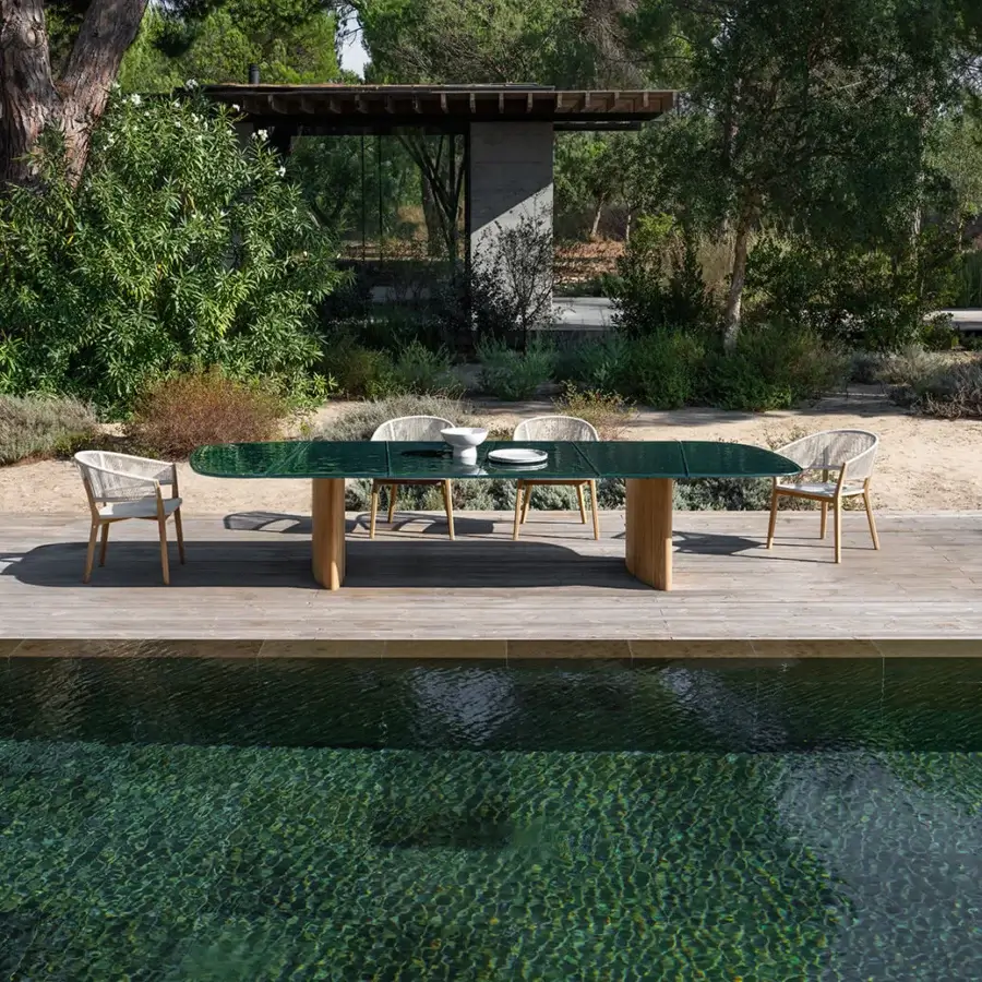 Superior Royal Botania Regaliz table with a textured clear glass top and light-colored teak bases crafted with a satin finish