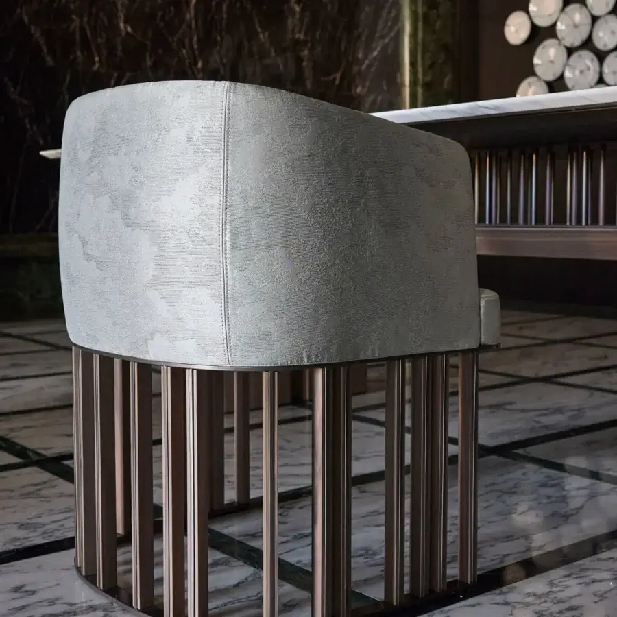 Lavish Giorgetti Hero chair with muted gray textile upholstery and a canaletto walnut base with satin sheen bronze-toned metal accents