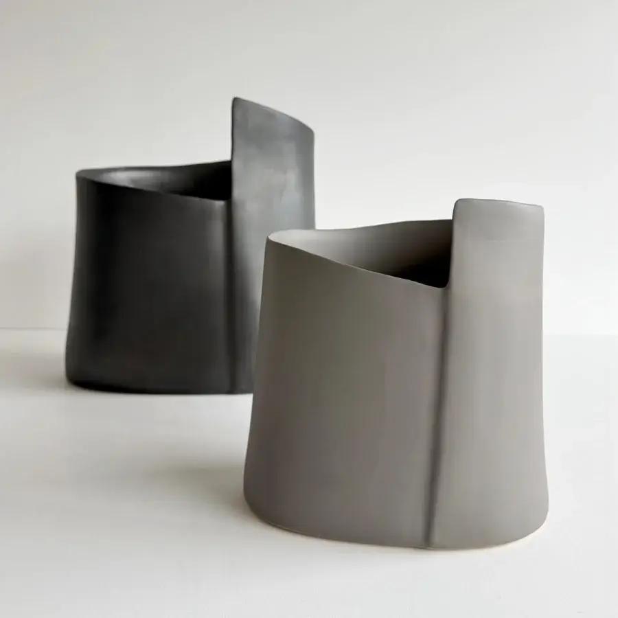 Captivating Rina Menardi Torri vase sculpted in baked clay with a subtly textured surface and organically waved opening in dark gray with a matte finish