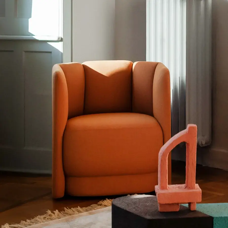 Sophisticated Bross Velia lounge chair with comfortably curved form upholstered in textured muted orange fabric