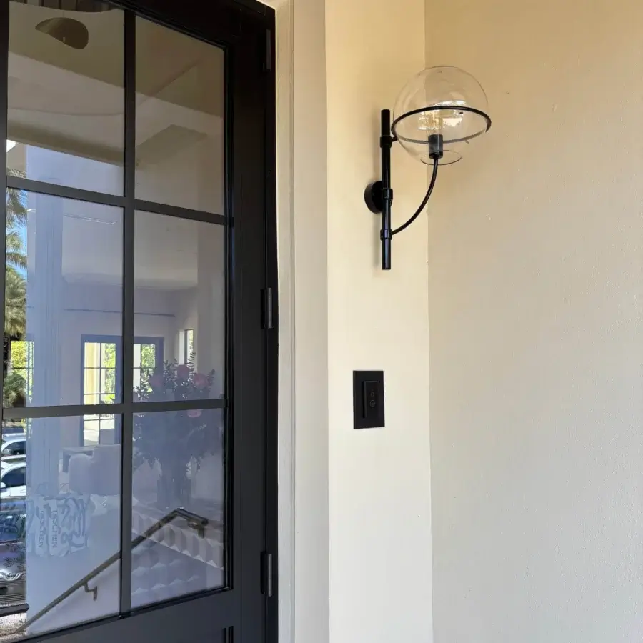 Elegant Oluce Lyndon wall lamp with a matte black metal frame supporting transparent polycarbonate spheres