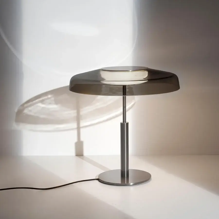Elegant Oluce Dora lamp embodies Italian design with a silver-grey glass cap lampshade and slender metal body
