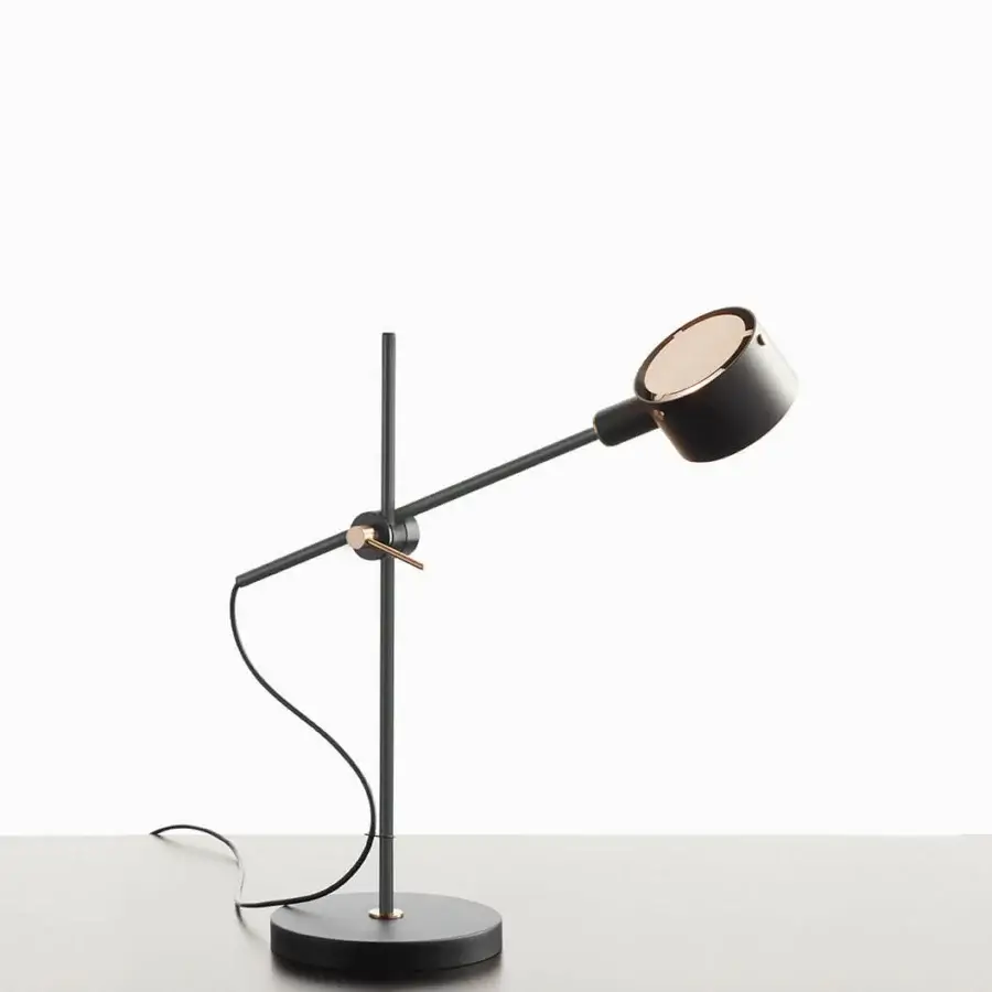 Superior Oluce G.O table lamp crafted in black metal with warm metallic accents and a cylindrical lampshade