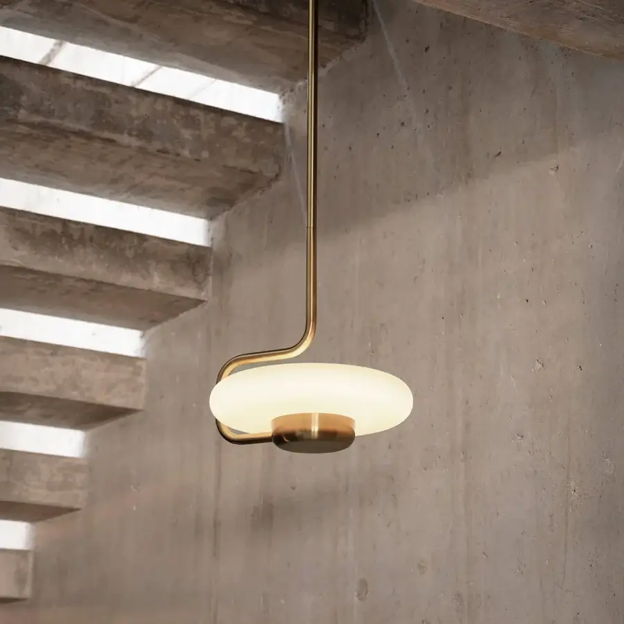 Elegant Kundalini Tratto suspension lamp with a gracefully curved form and warm muted gold metal with opal glass construction and satin finish
