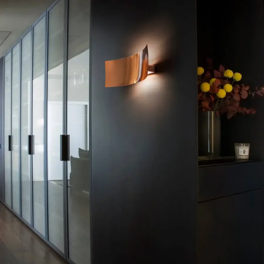 Elegant Oluce Lens wall lamp in curved metal with warm copper finish and satin texture