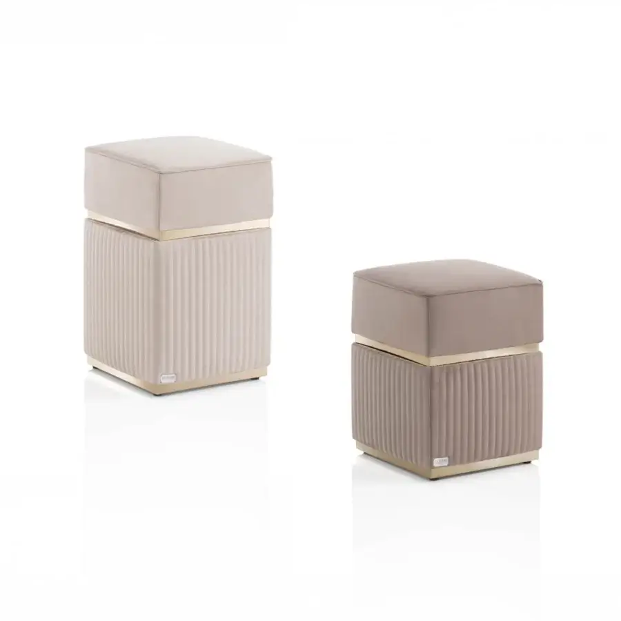 Square velvet ottomans, light taupe finish, with gold metal band and ribbed rectangular base, displaying brand plaque detail.