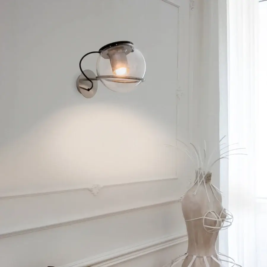 Elegant Oluce Globe wall lamp crafted in Italy with a transparent blown-glass globe and dark matte metal reflector