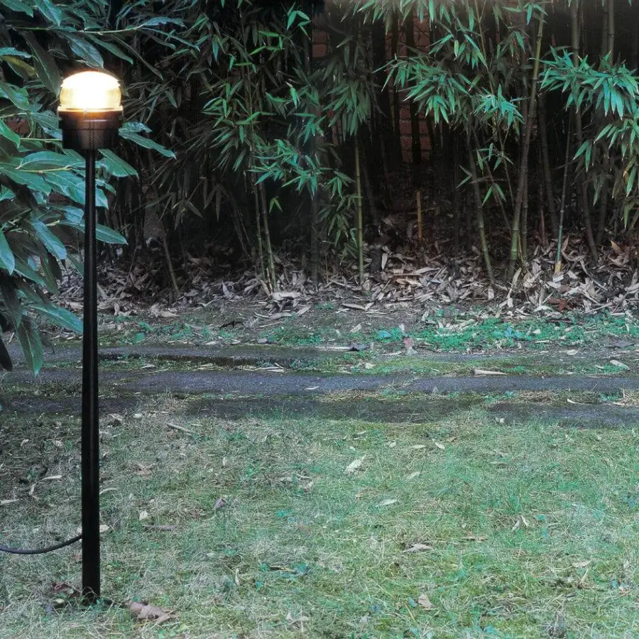 Exclusive Oluce Fresnel floor lamp with matte black metal body and warm amber ribbed lens-like shade
