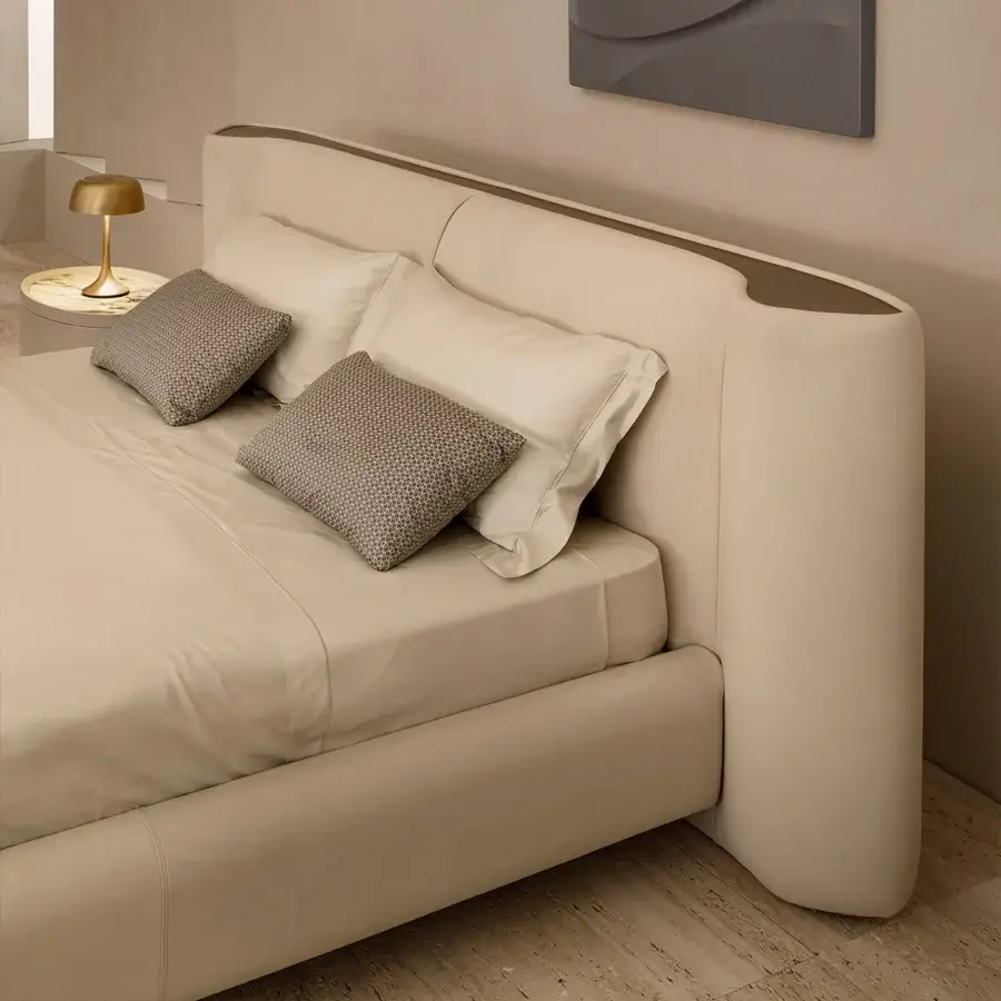 Exclusive Rugiano Anais bed with a rounded headboard and plush frame upholstered in neutral beige fabric with bronzed brass details
