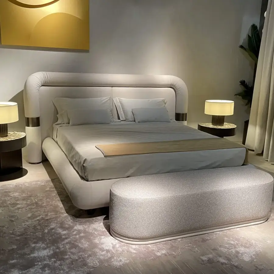 Distinguished Rugiano Loom bed with a continuously curved headboard upholstered in a light neutral beige and bronzed brass accents