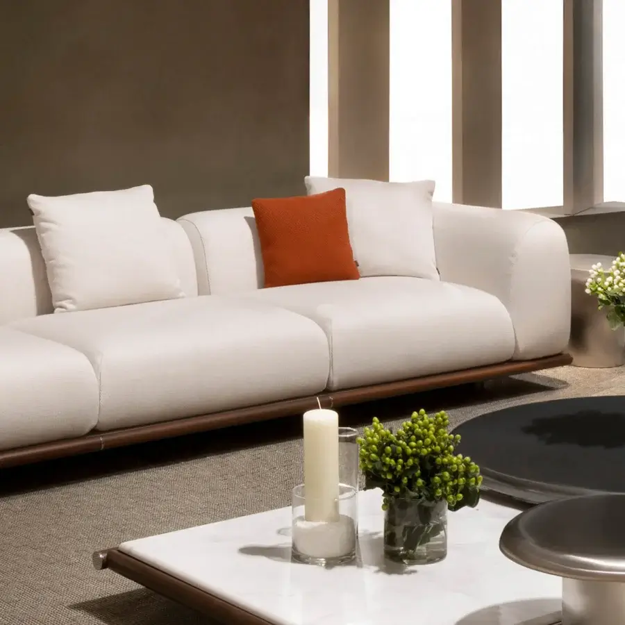 Superior Rugiano Amalfi sofa with stained mahogany, chrome details, light neutral fabric, and a reddish-orange accent cushion