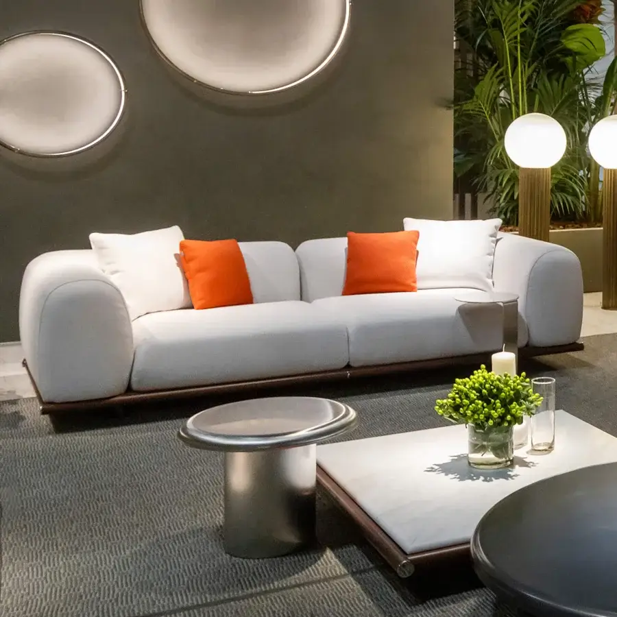 Distinguished Rugiano Amalfi sofa with warm stained mahogany, crisp chrome details, and vibrant orange cushions in durable off-white fabric