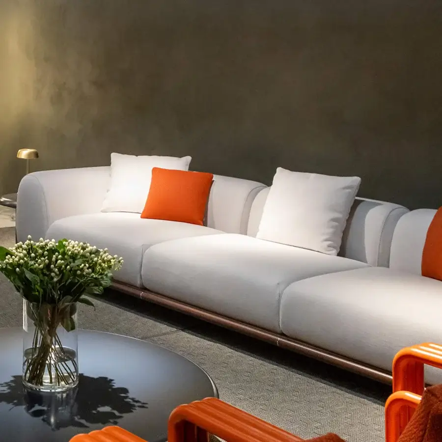Superior Rugiano Amalfi sofa with warm stained mahogany, chrome details, off-white fabric, and vibrant orange cushions