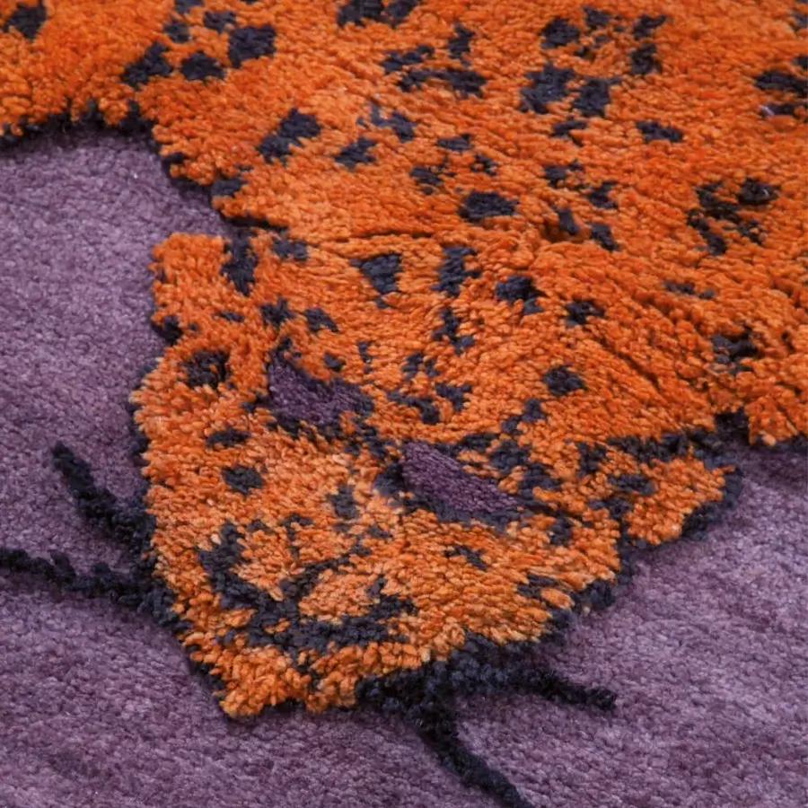 Superior Amini Tapipardo rug with orange and dark spots against a muted purple, hand-knotted pure wool with carved texture